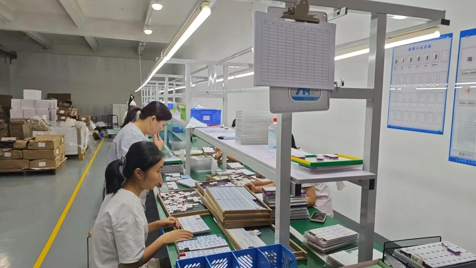 Factory-supplied photograph of mahjong tile assembly and inspection workbenches